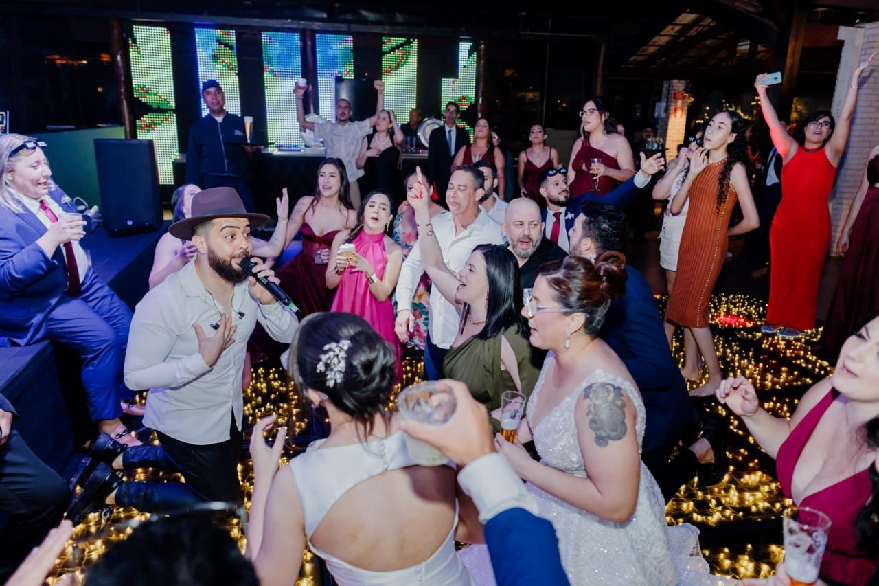 Noivas e convidados cantando na pista em frente ao palco